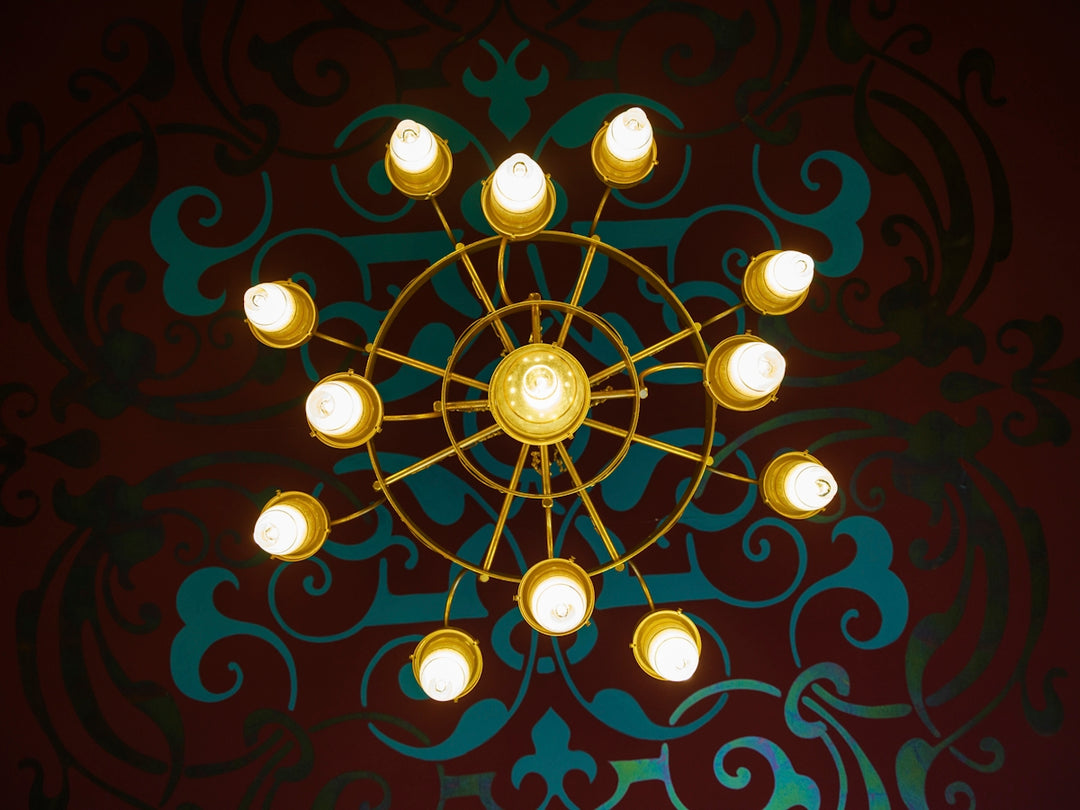 A golden chandelier illuminates against a patterned background.