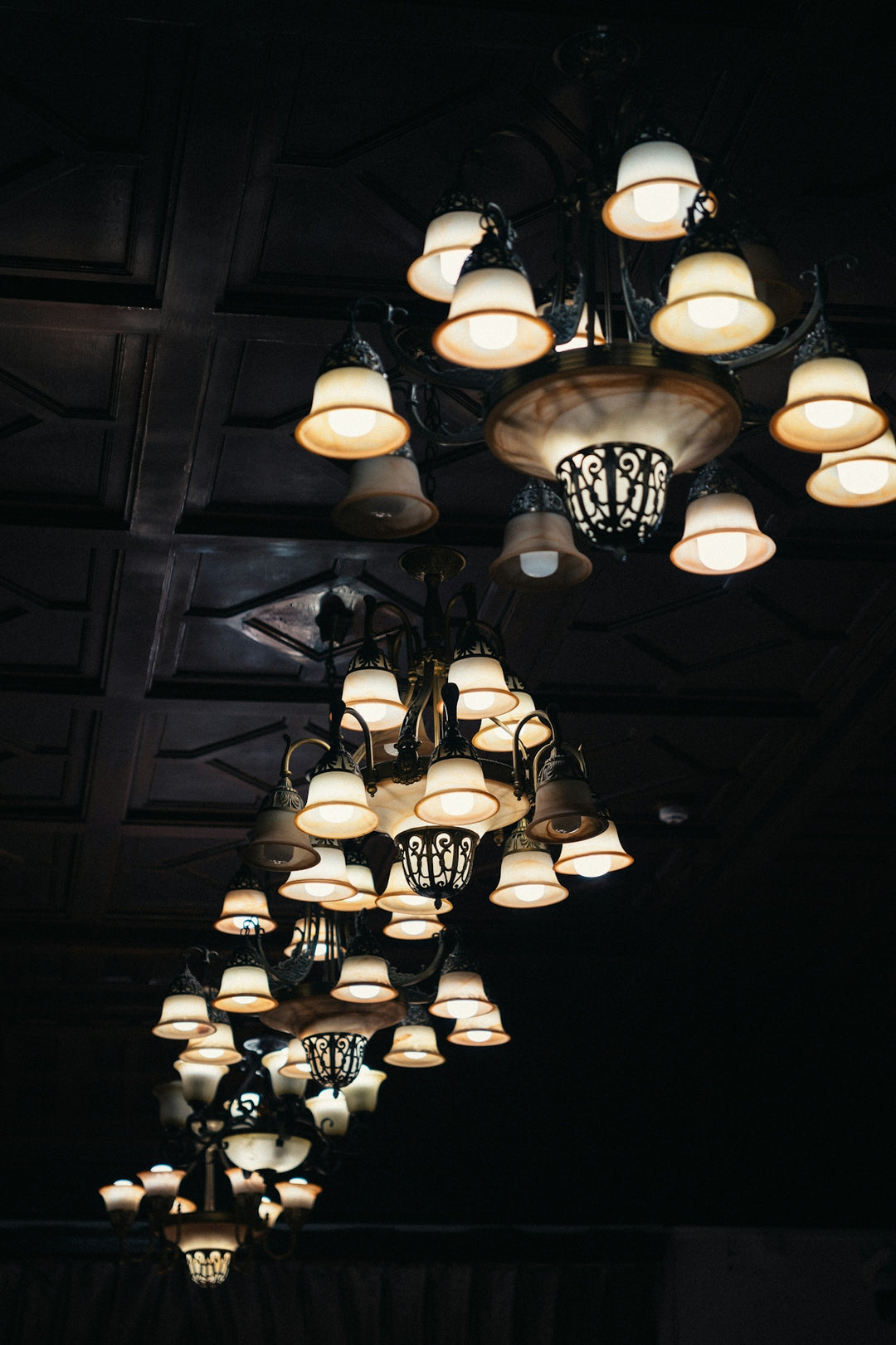 Ornate chandeliers hanging from a dark ceiling