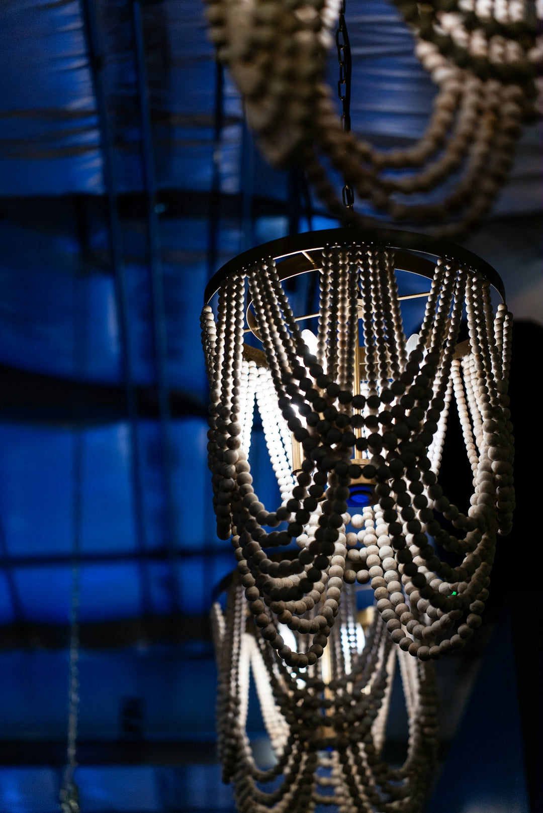 Ornate beaded chandeliers hang against a blue background.