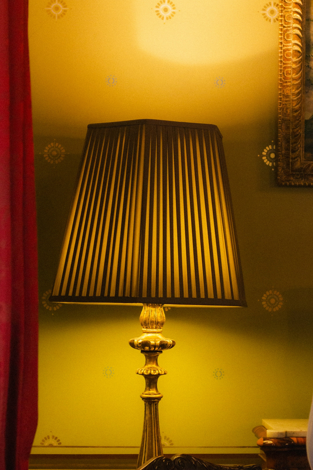 A vintage lamp with a pleated shade illuminates a room.
