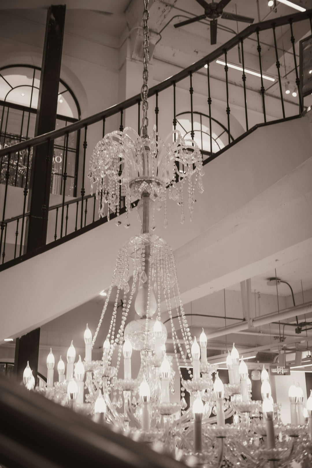 An ornate crystal chandelier hangs near a staircase