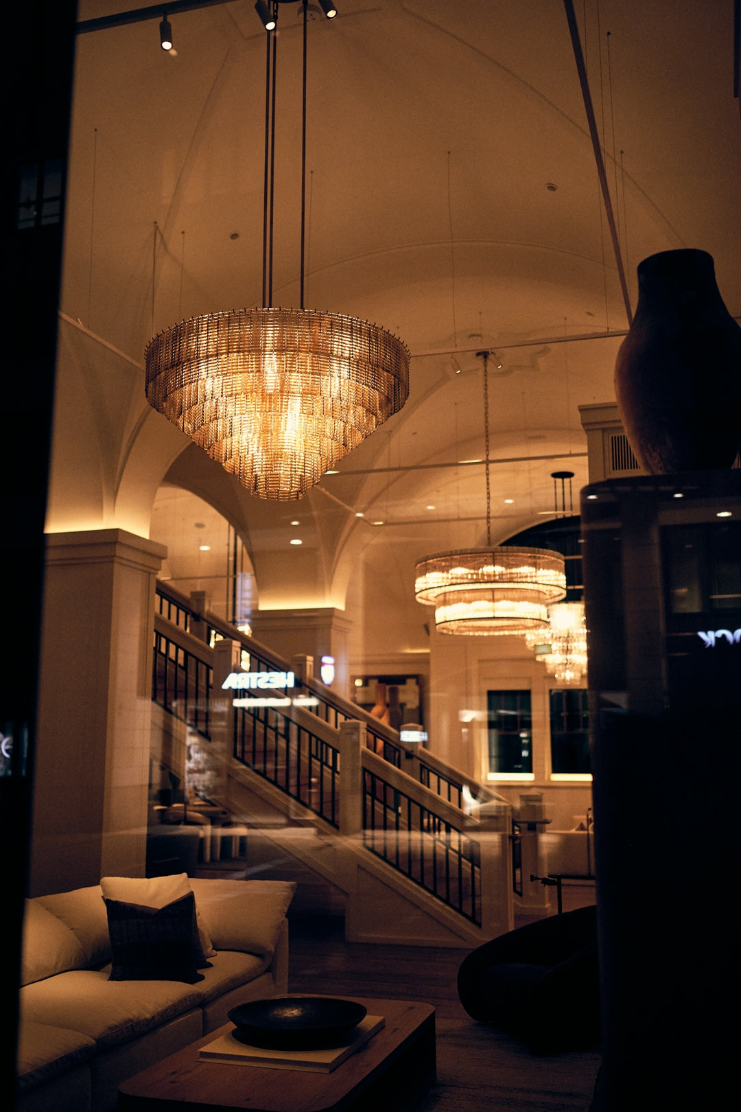 Ornate chandelier illuminates a luxurious interior with a grand staircase.