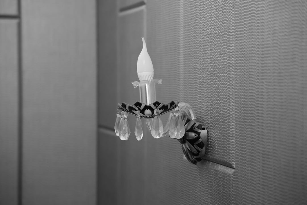 A decorative crystal wall sconce with a candle bulb.