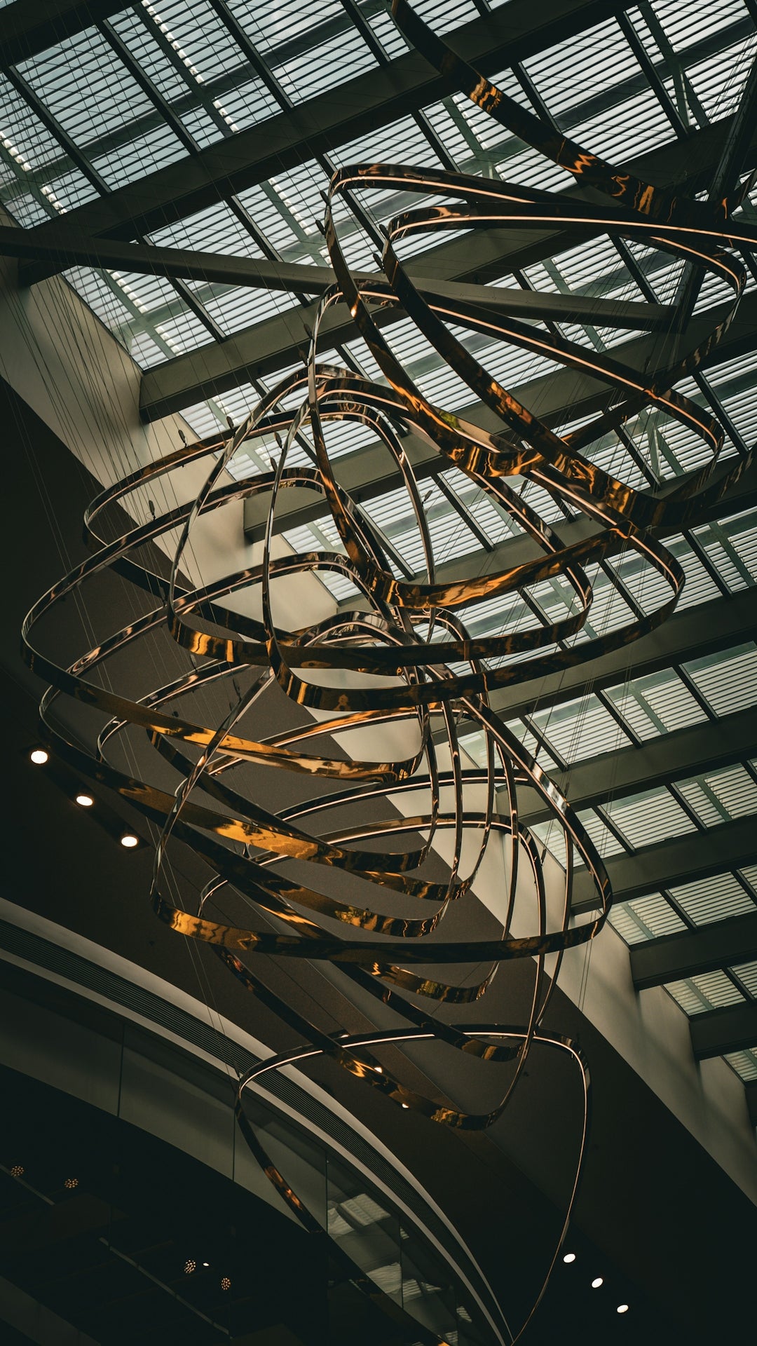 Modern golden ring chandelier hanging from a high ceiling.