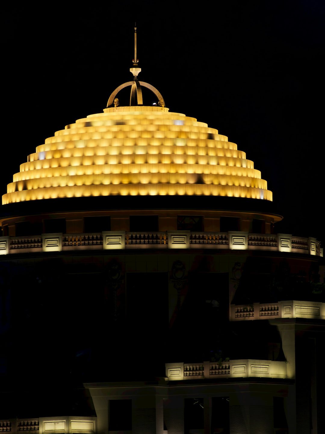 A golden illuminated dome of a building at night.