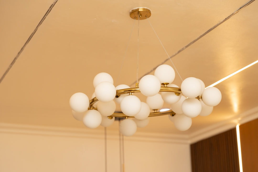 Contemporary gold chandelier featuring many white globe lights.