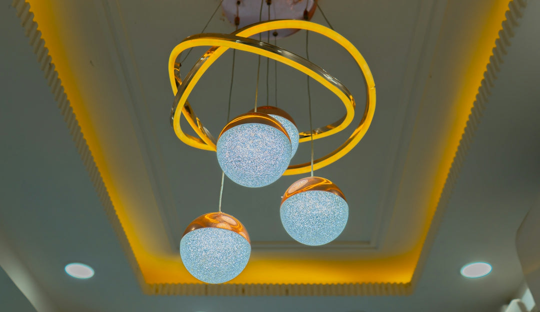 A modern chandelier with three glowing textured glass spheres and gold rings